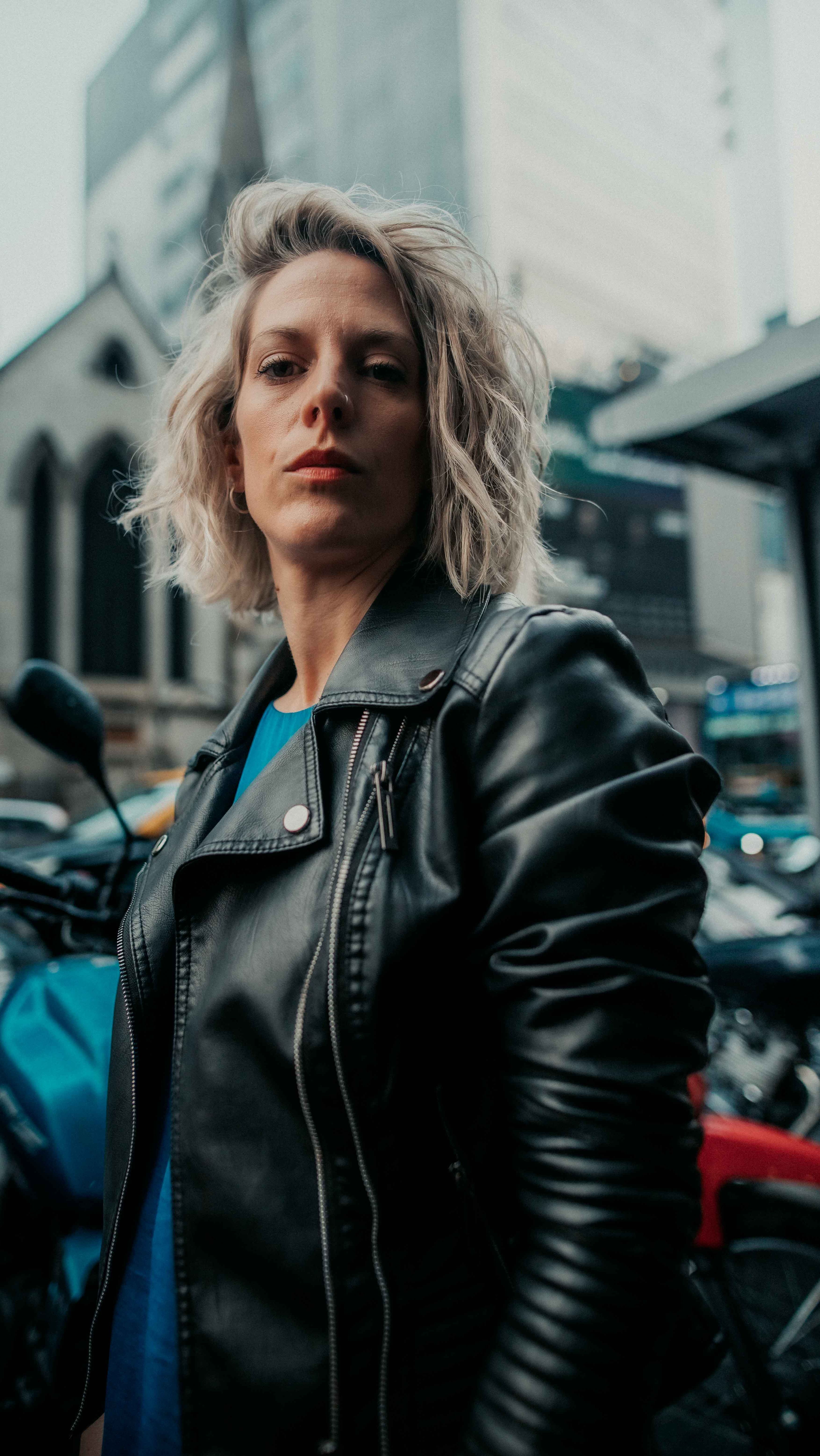 A woman in a black leather jacket standing in front of motorcycles ...