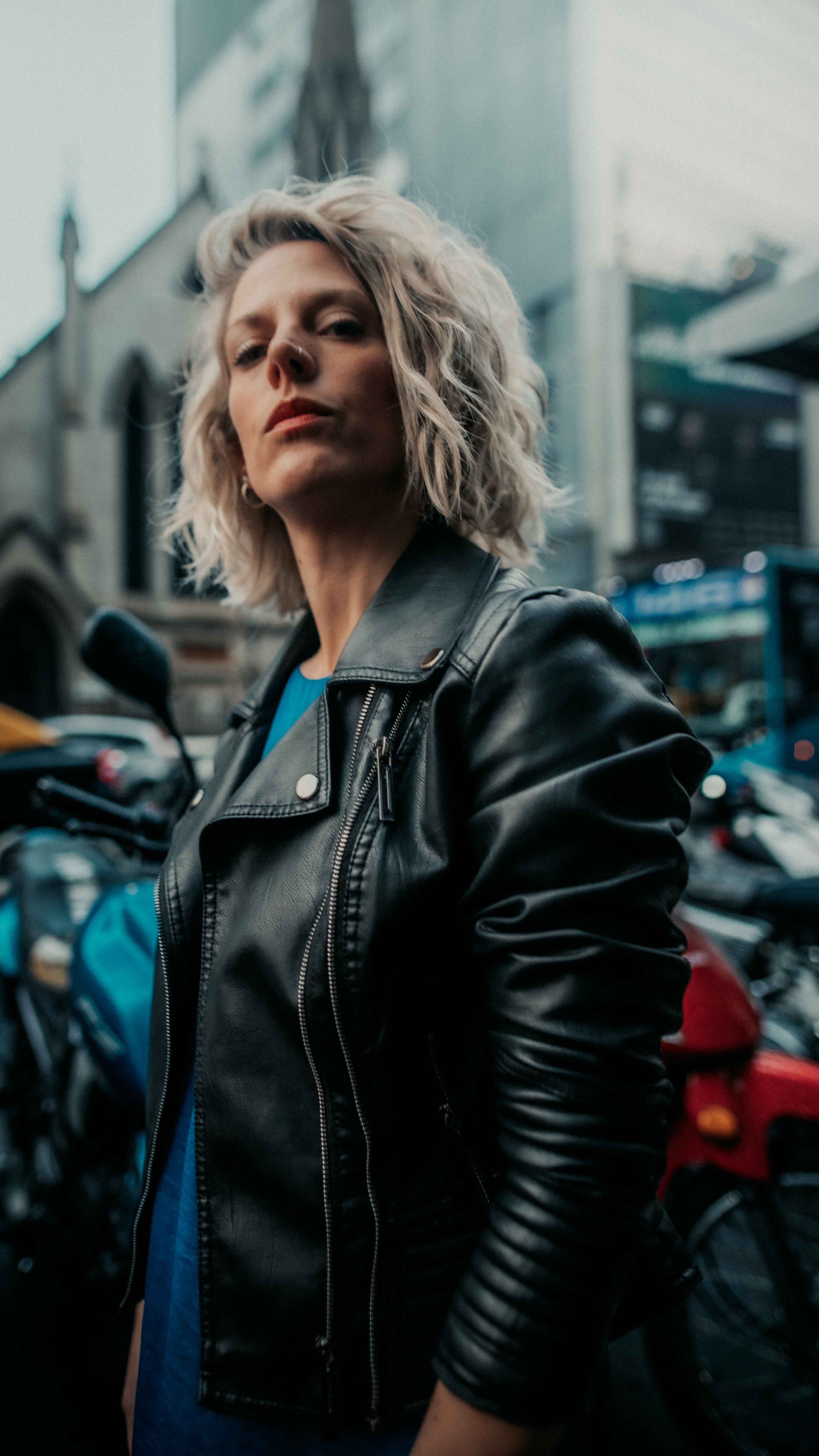 A woman in a black leather jacket standing in front of a group of ...