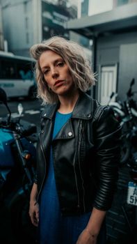 Stylish portrait of a young woman in a leather jacket on a city street.