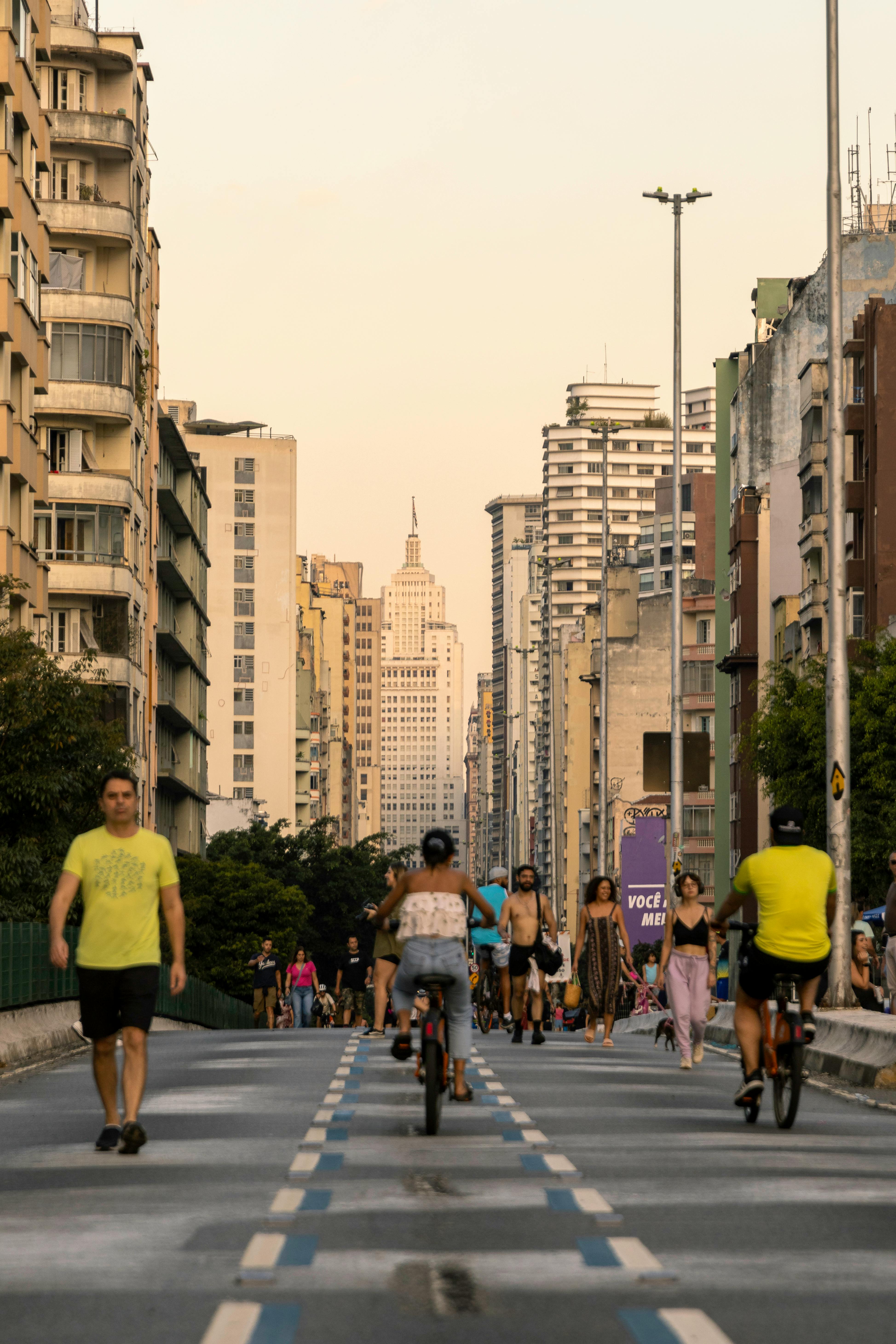 people riding bikes on a city street with tall buildings