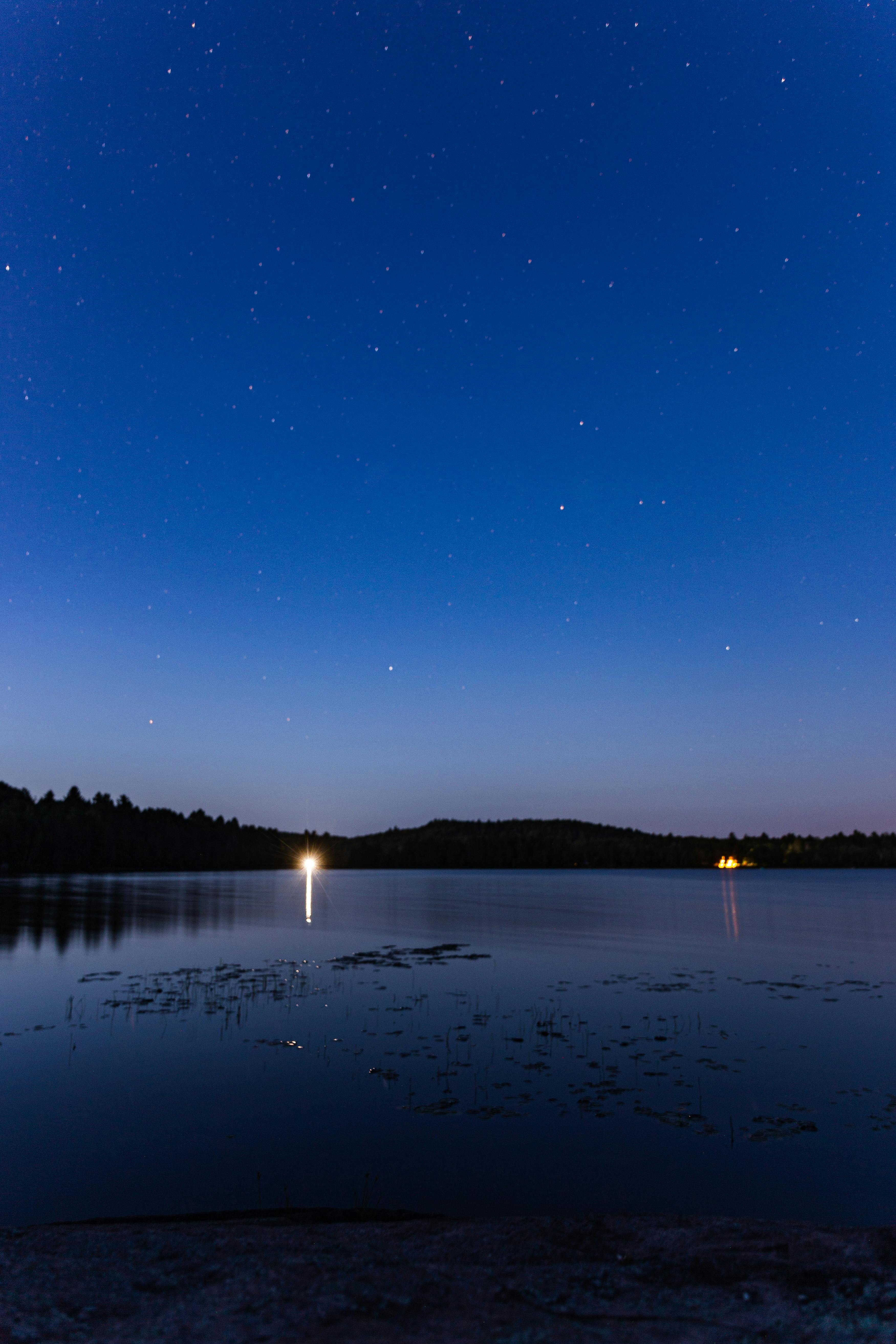 宁静的夜空与星空倒映在湖泊中，树木的剪影清晰可见