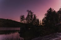 暮色中，湖面宁静，树影婆娑，一弯新月挂在天边