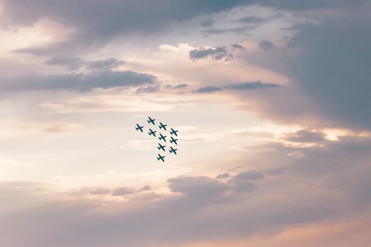 A dramatic image of aircrafts flying in a formation against a colorful sunset sky.