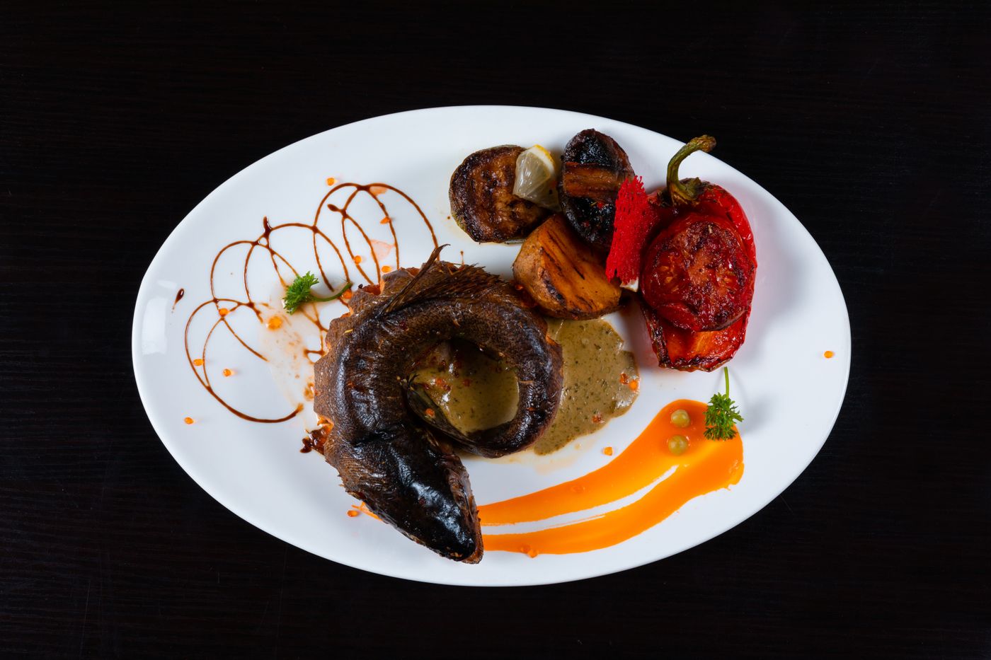 Elegant plate of roasted meat and vegetables with artistic sauce design.