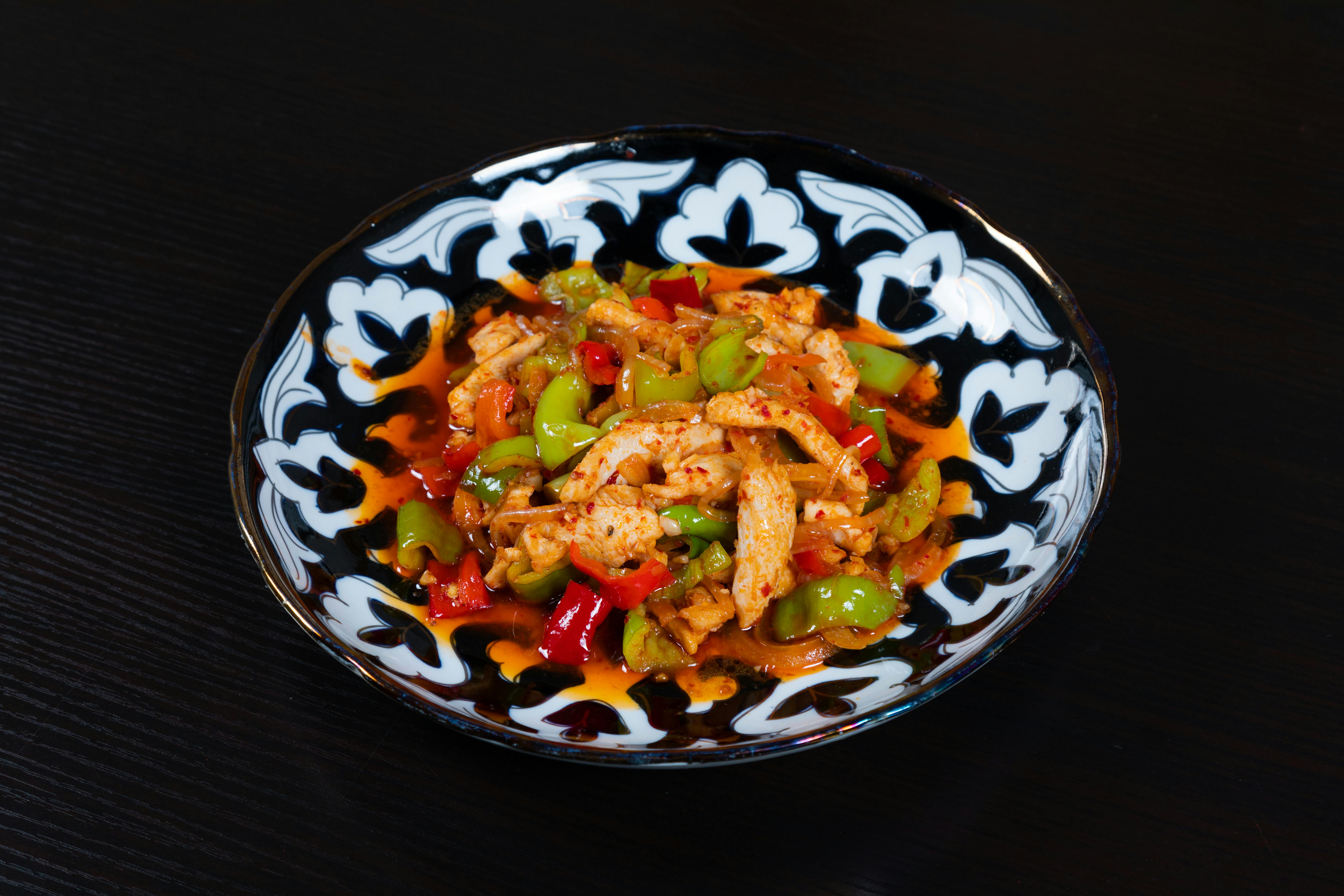 a bowl of food with chicken and peppers on it