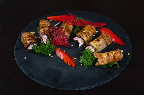 Free A gourmet dish of grilled meat rolls and fresh vegetables on a slate platter. Stock Photo