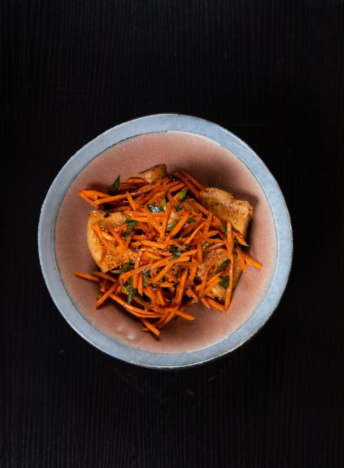 Free A bird's-eye view of a gourmet carrot and potato dish with herbs, served in a rustic bowl on a dark wooden table. Stock Photo
