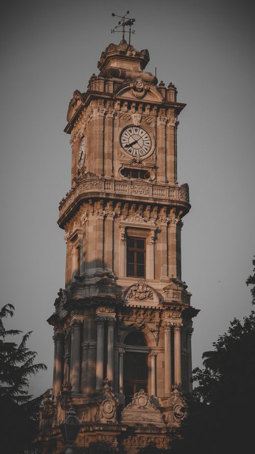 Free Gothic-style clock tower under the twilight sky, highlighting intricate architectural details. Stock Photo