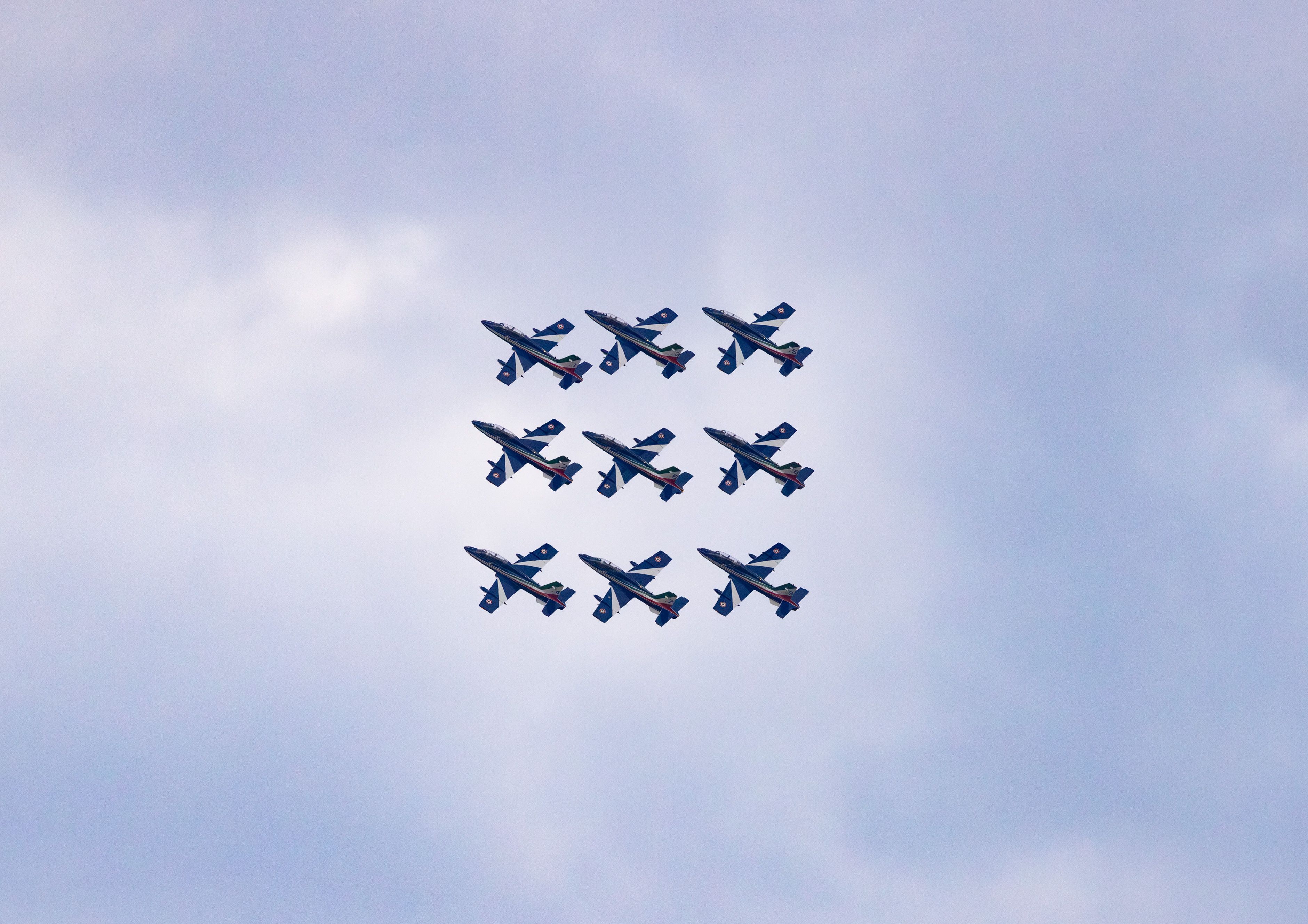 A squadron of military jets flying in formation against a cloudy sky.