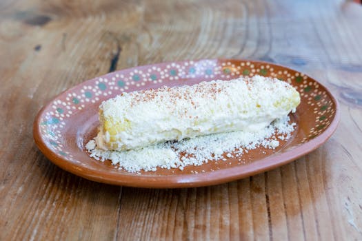 Delicious Mexican elote with cheese and spices served on a traditional plate.