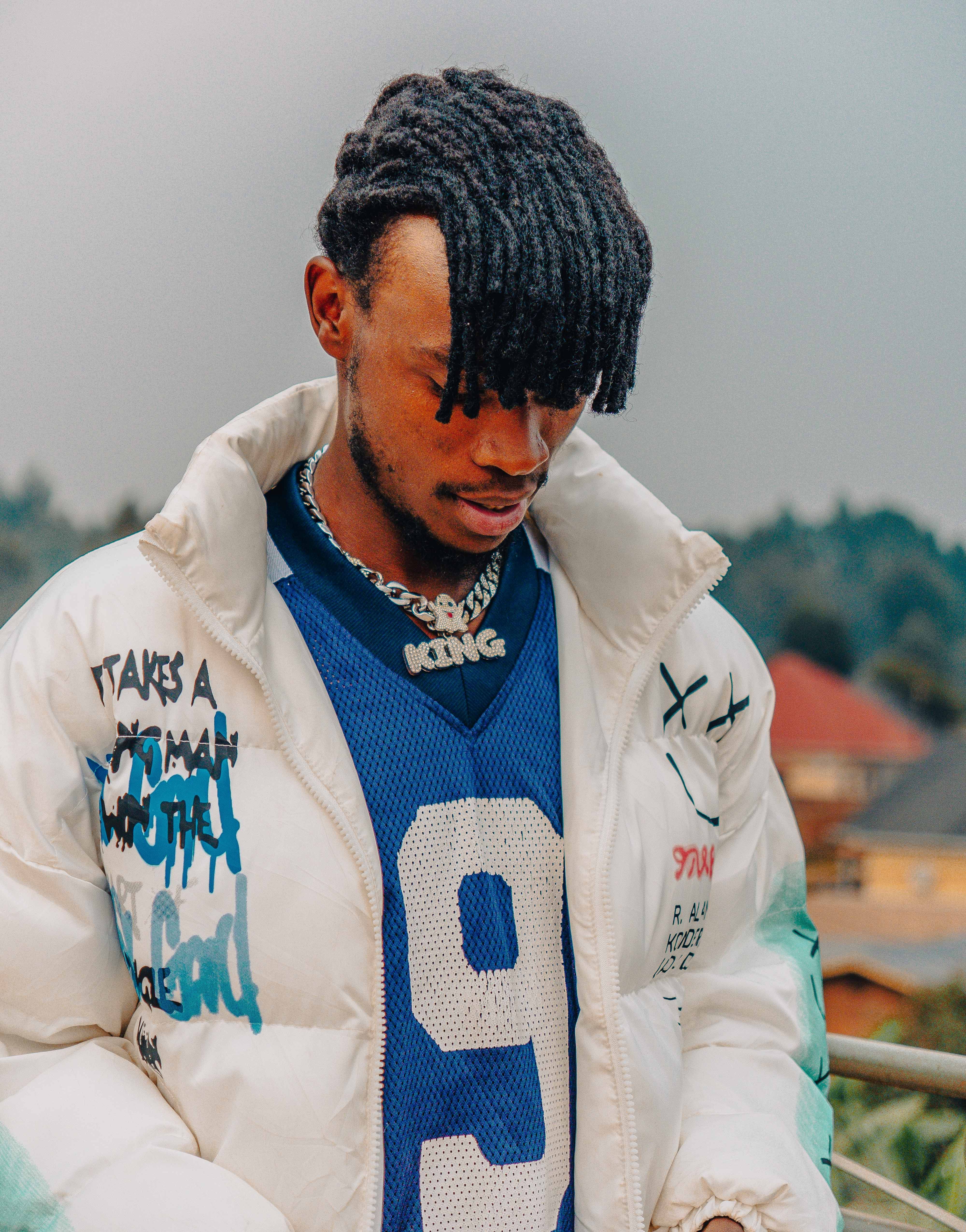 Trendy man with dreadlocks and sportswear jacket standing outdoors, showcasing urban fashion.