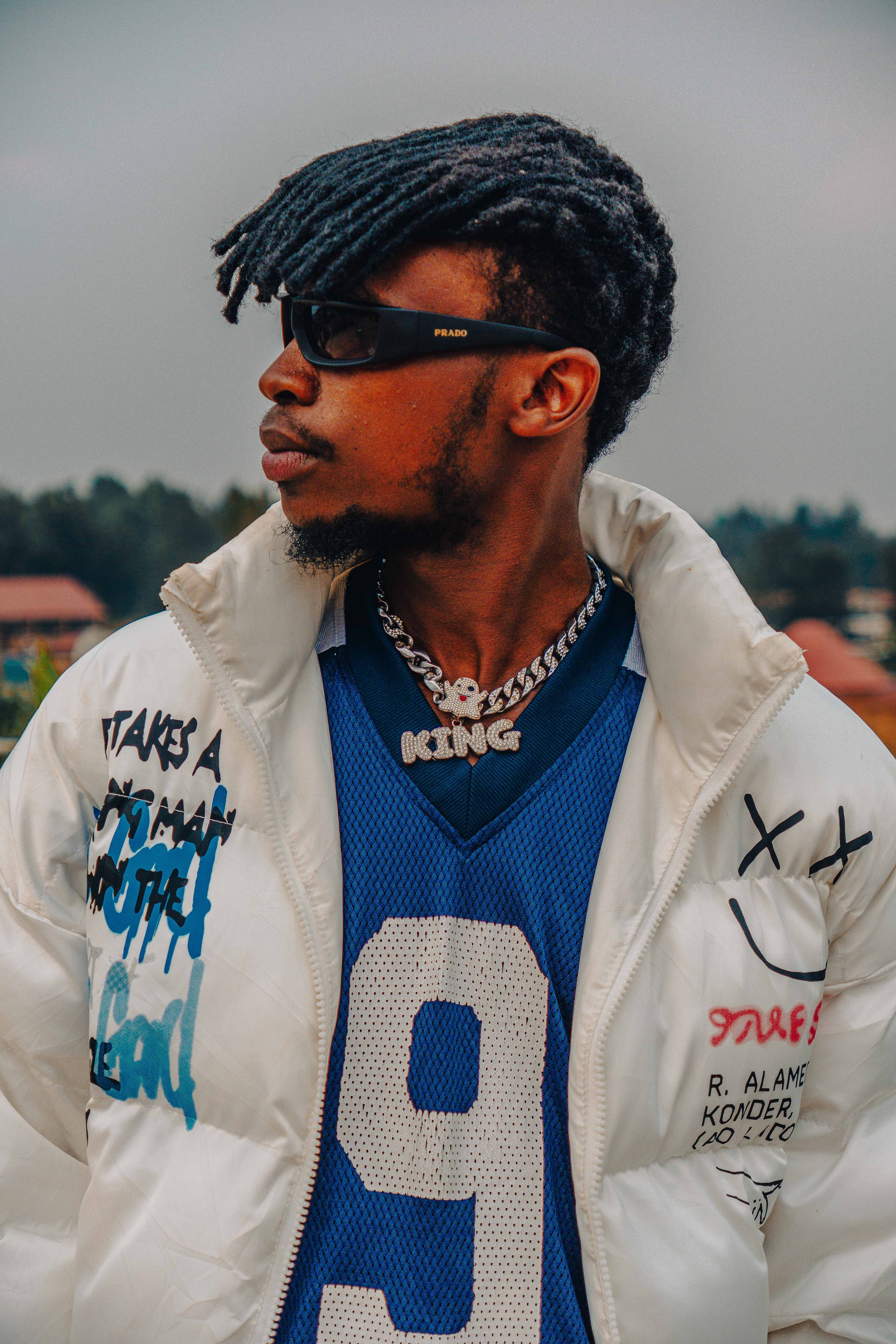 A fashionable man wearing sunglasses and a graffiti jacket for a modern urban look.