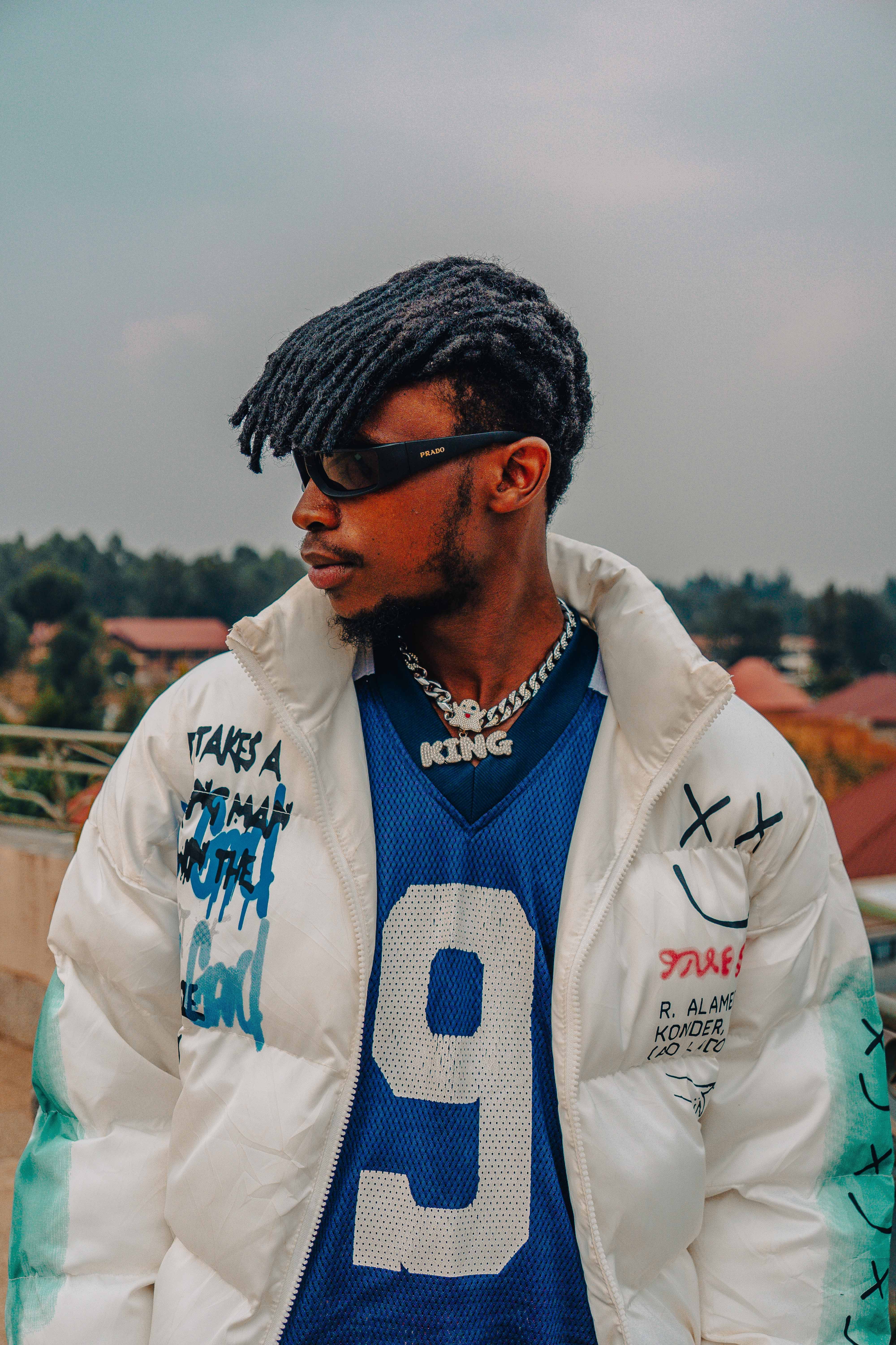 Fashion-forward urban portrait featuring a man wearing a jersey and artistic jacket.
