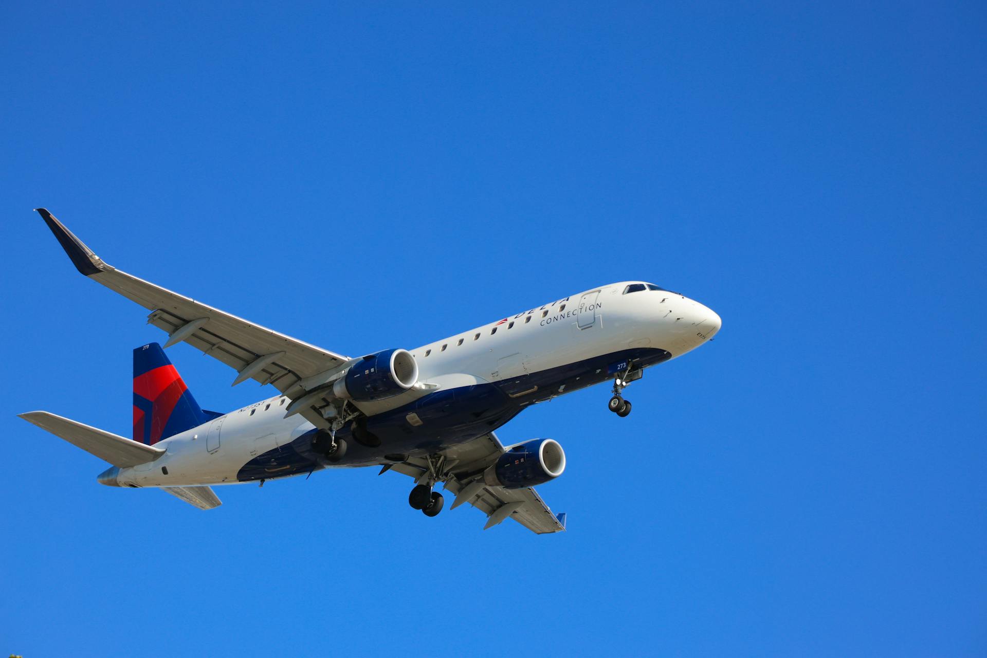 A delta airplane flying in the sky with a blue sky