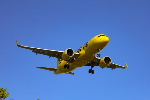 Free Vibrant yellow airplane captured mid-flight against a clear blue sky, symbolizing travel and aviation. Stock Photo