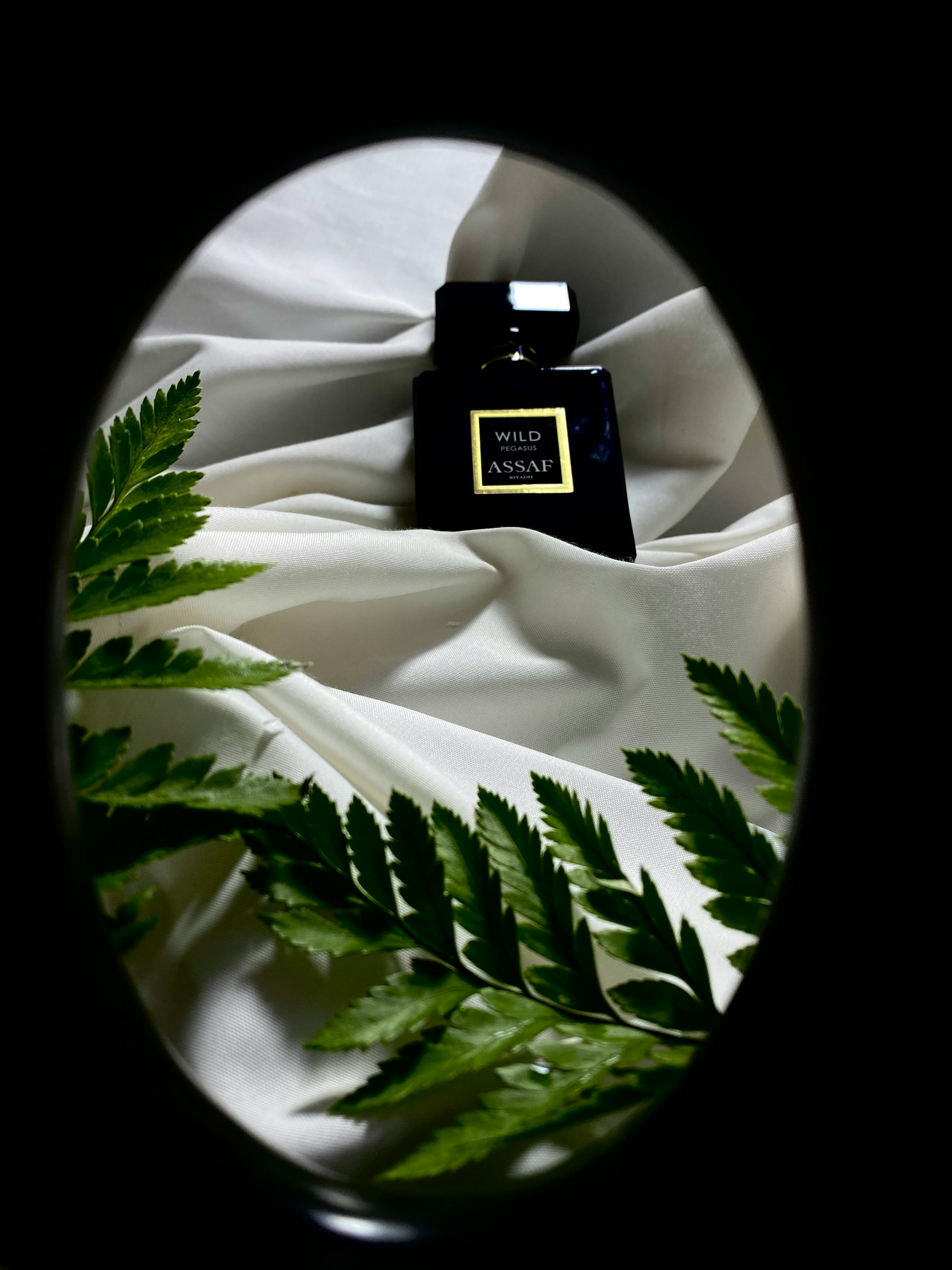 Luxurious perfume bottle surrounded by green leaves on white fabric, showcasing elegance and sophistication.