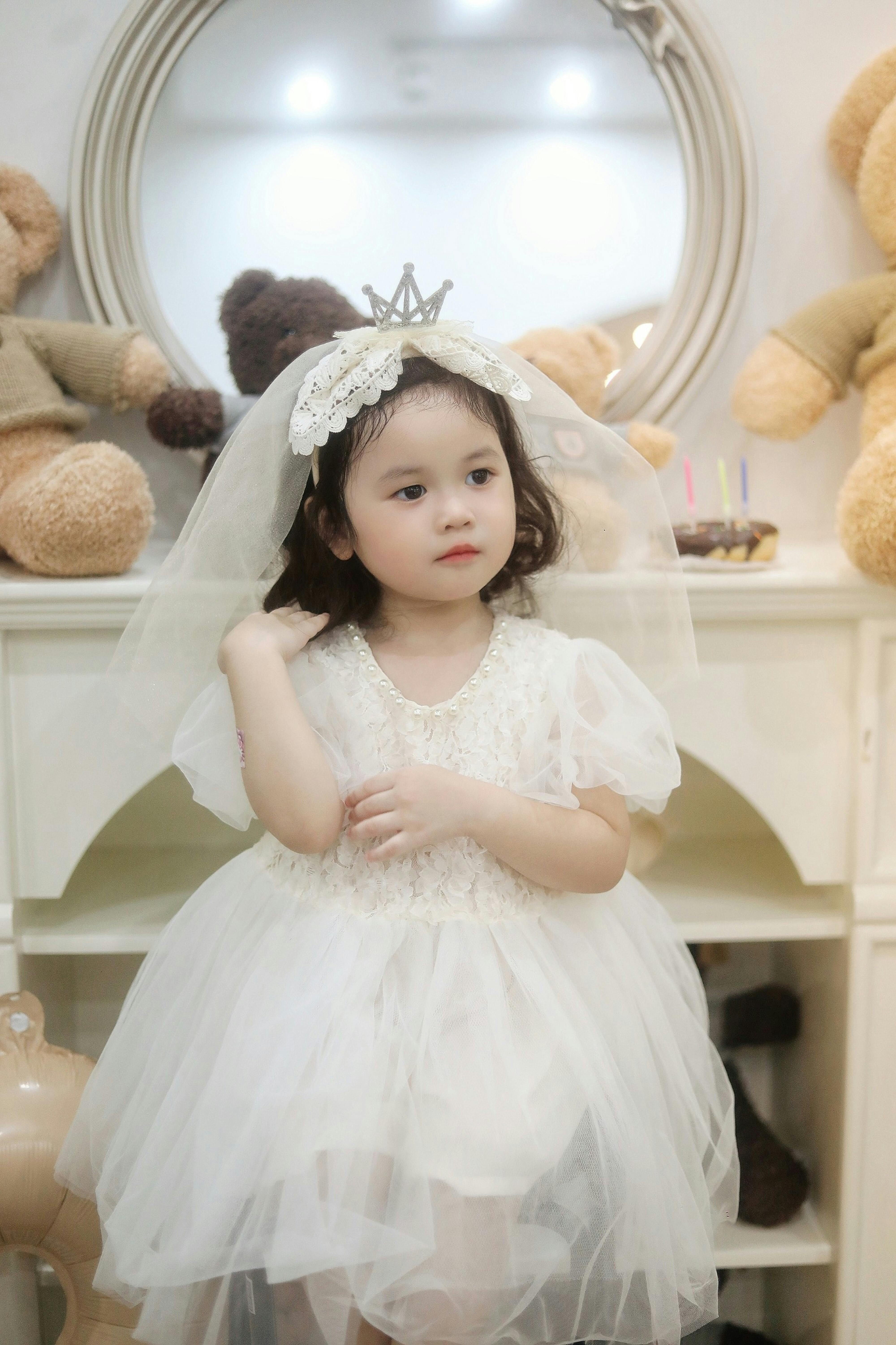 a little girl wearing a white dress and tiara