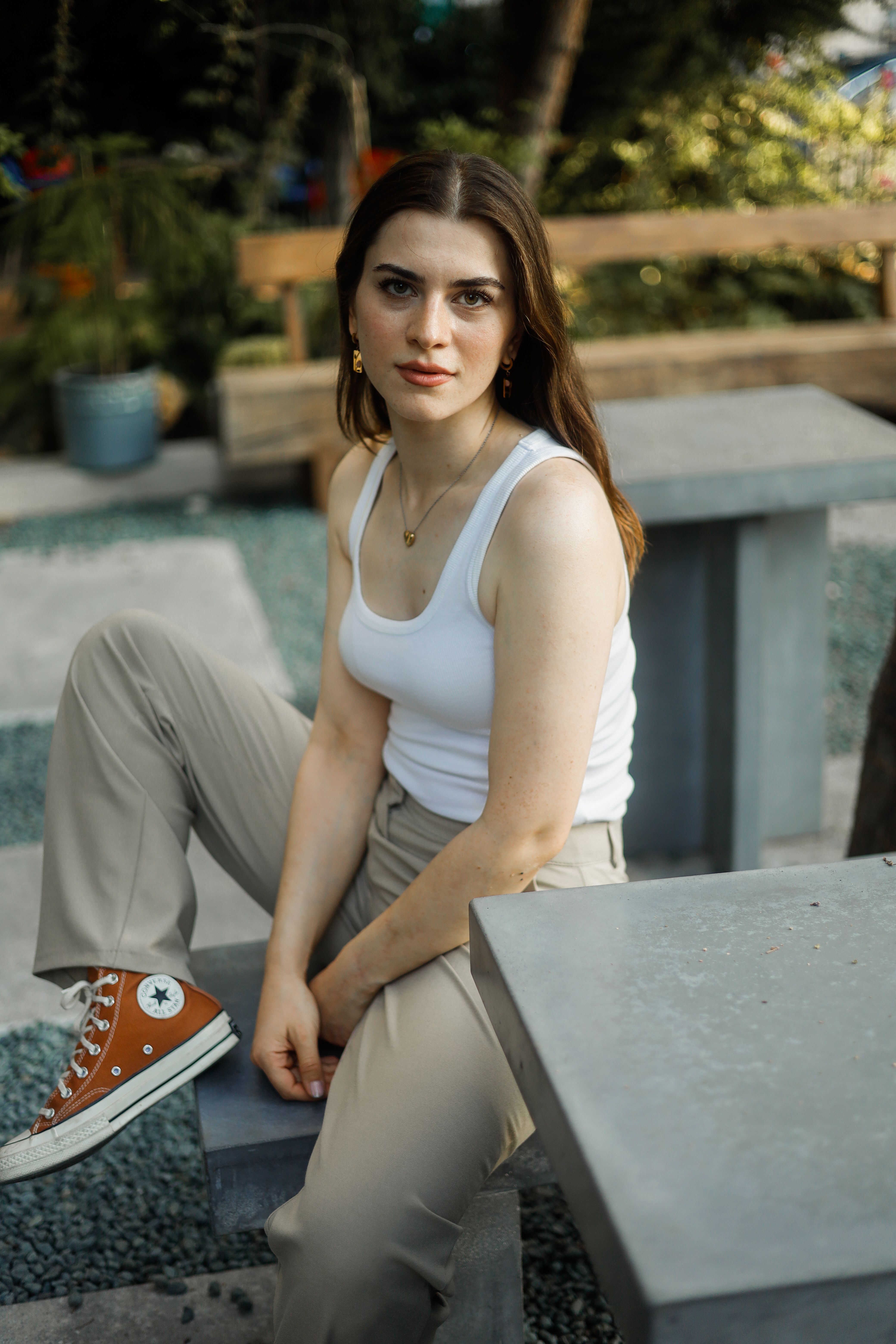 A woman sitting on a bench wearing converse shoes · Free Stock Photo