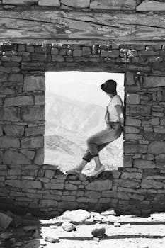A person sits in a stone window with scenic mountain view in Dagestan.