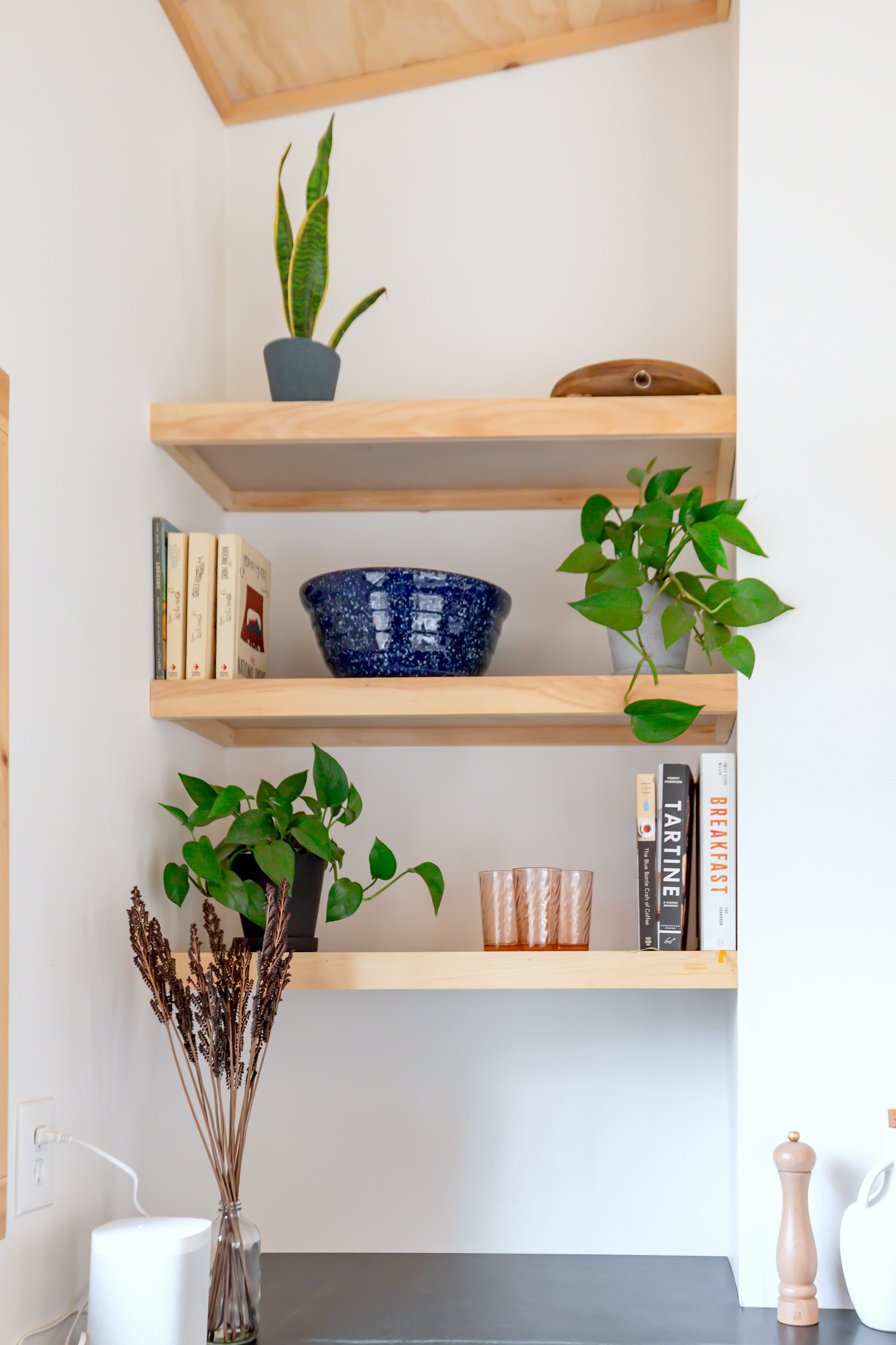 Minimalist wooden shelves with books, plants, and decor in modern interior design.