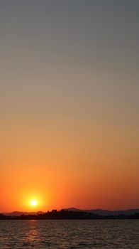 Capture of a tranquil sunset with the sun setting over a calm sea horizon.