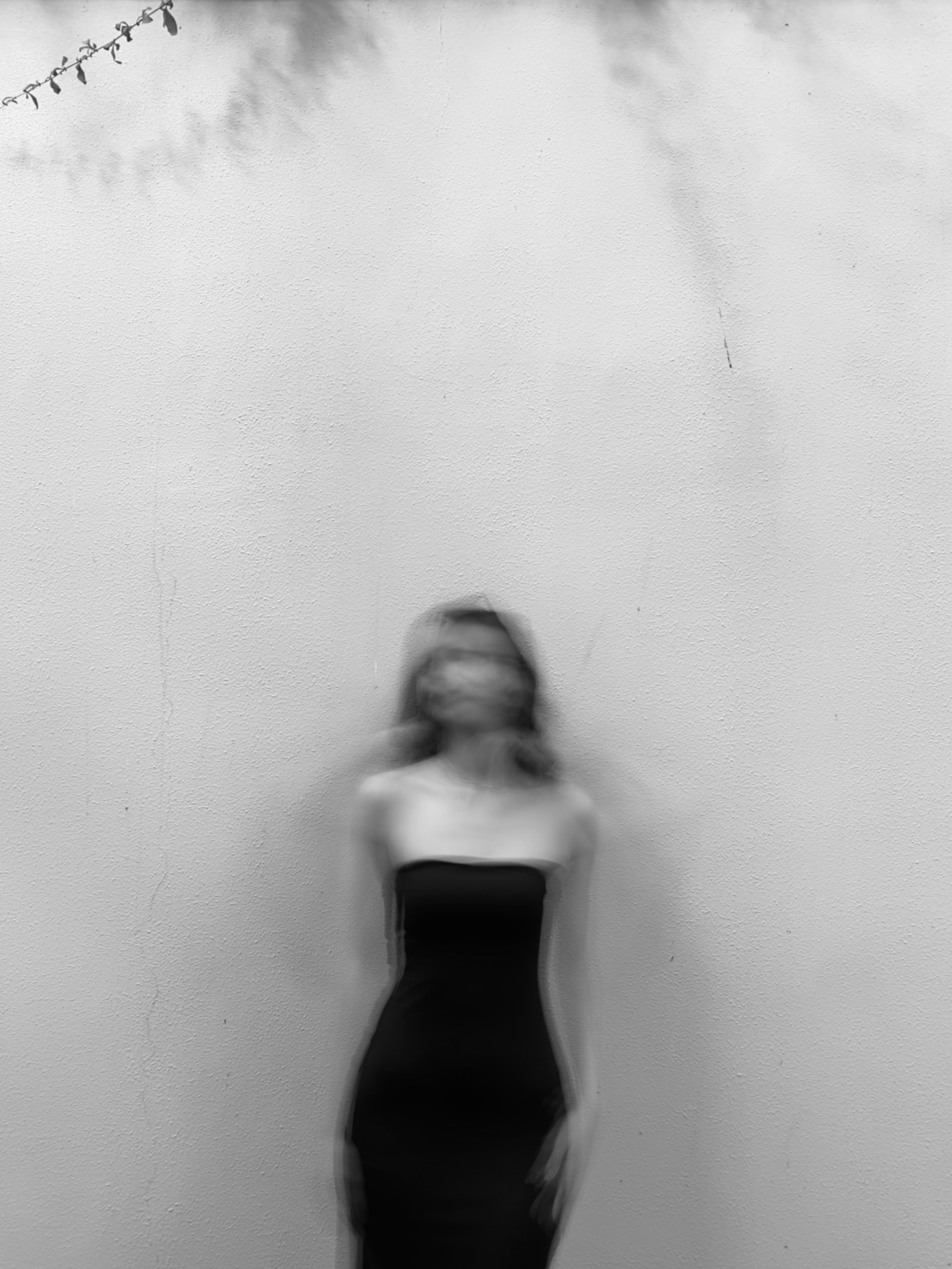 A woman in a black dress is standing in front of a wall · Free Stock Photo