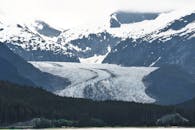 白雪皑皑的山脉和郁郁葱葱的森林环绕着阿拉斯加冰川的壮丽景色