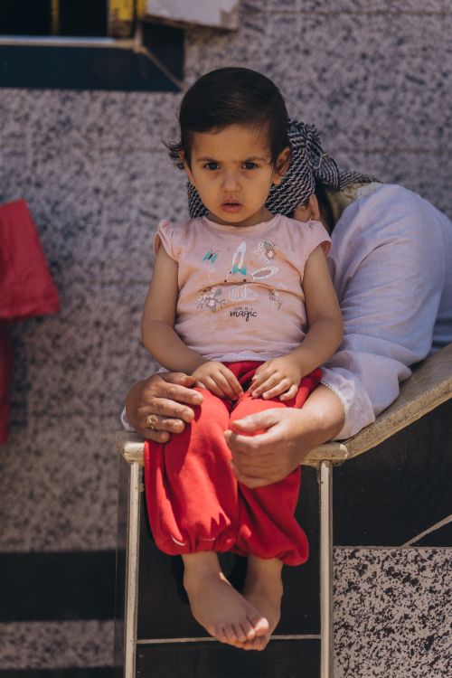 Free Cute toddler sitting on a lap outside in Kafr El-Shaikh, Egypt, showcasing innocence and cuteness. Stock Photo