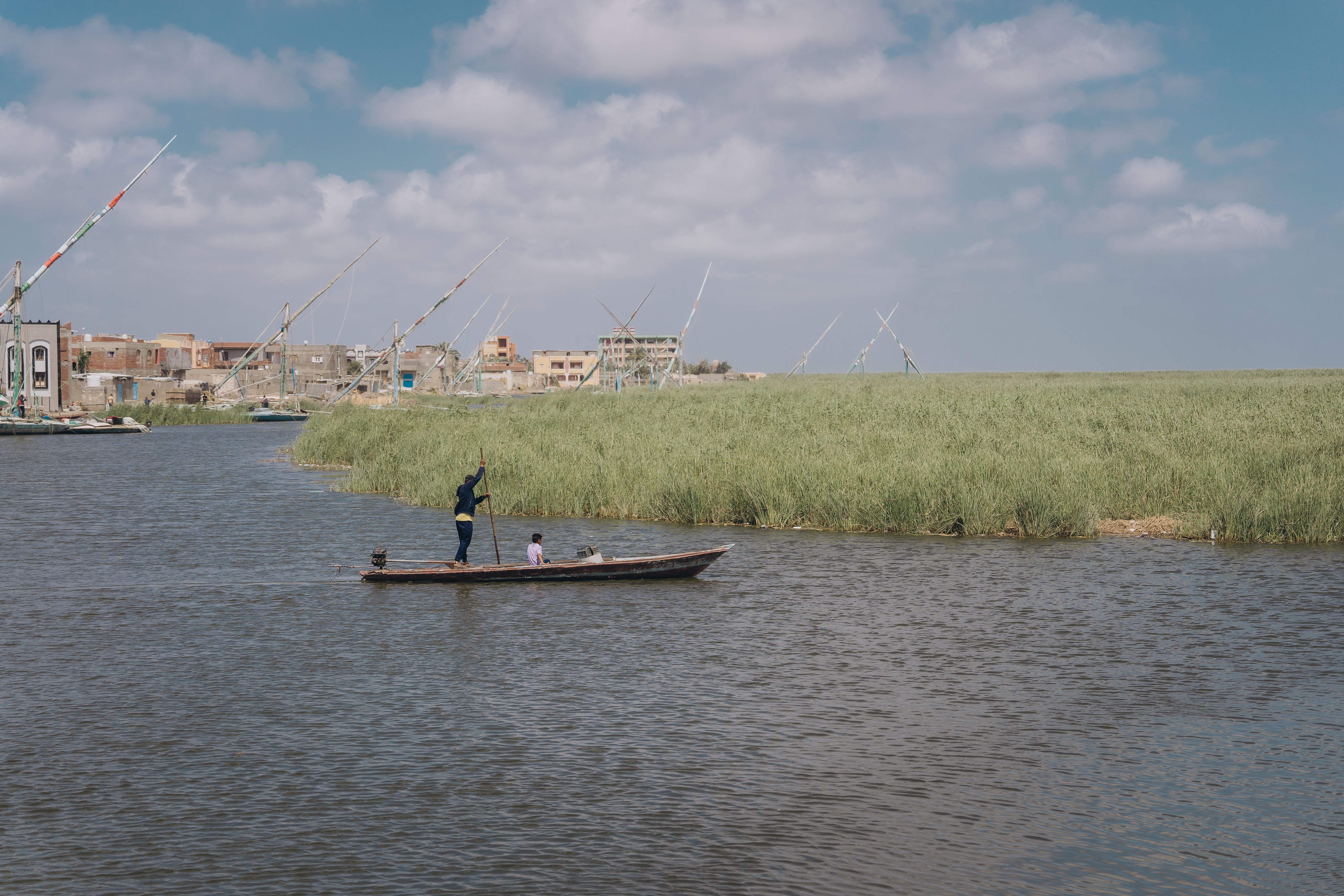A serene fishing boat on the Nile in Kafr El-Shaikh, Egypt, under a bright sky.