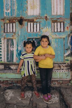 Two children standing against a colorful urban backdrop in Kafr El-Shaikh, Egypt.