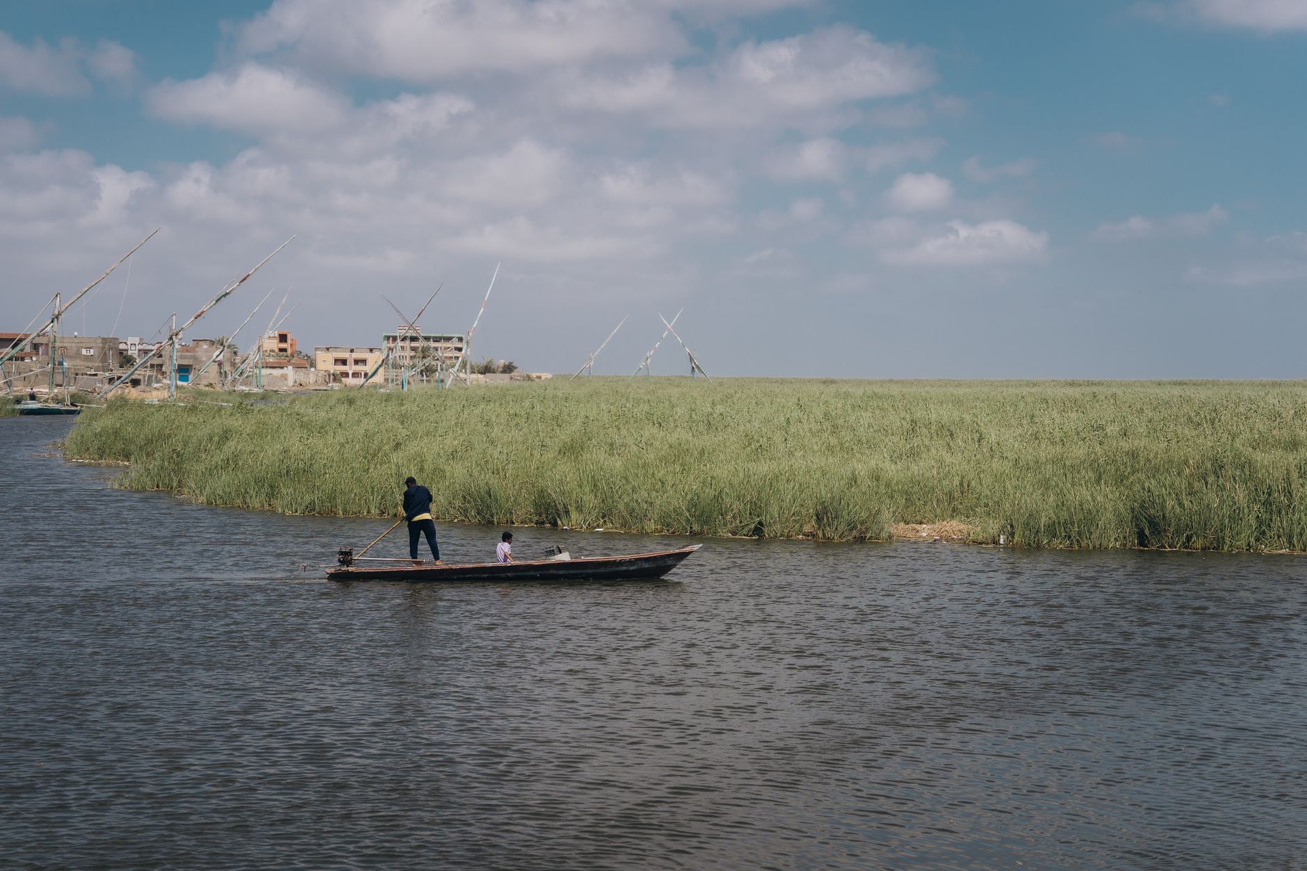 Local fishermen navigate the serene waters in Kafr El-Shaikh, Egypt, under a clear sky.