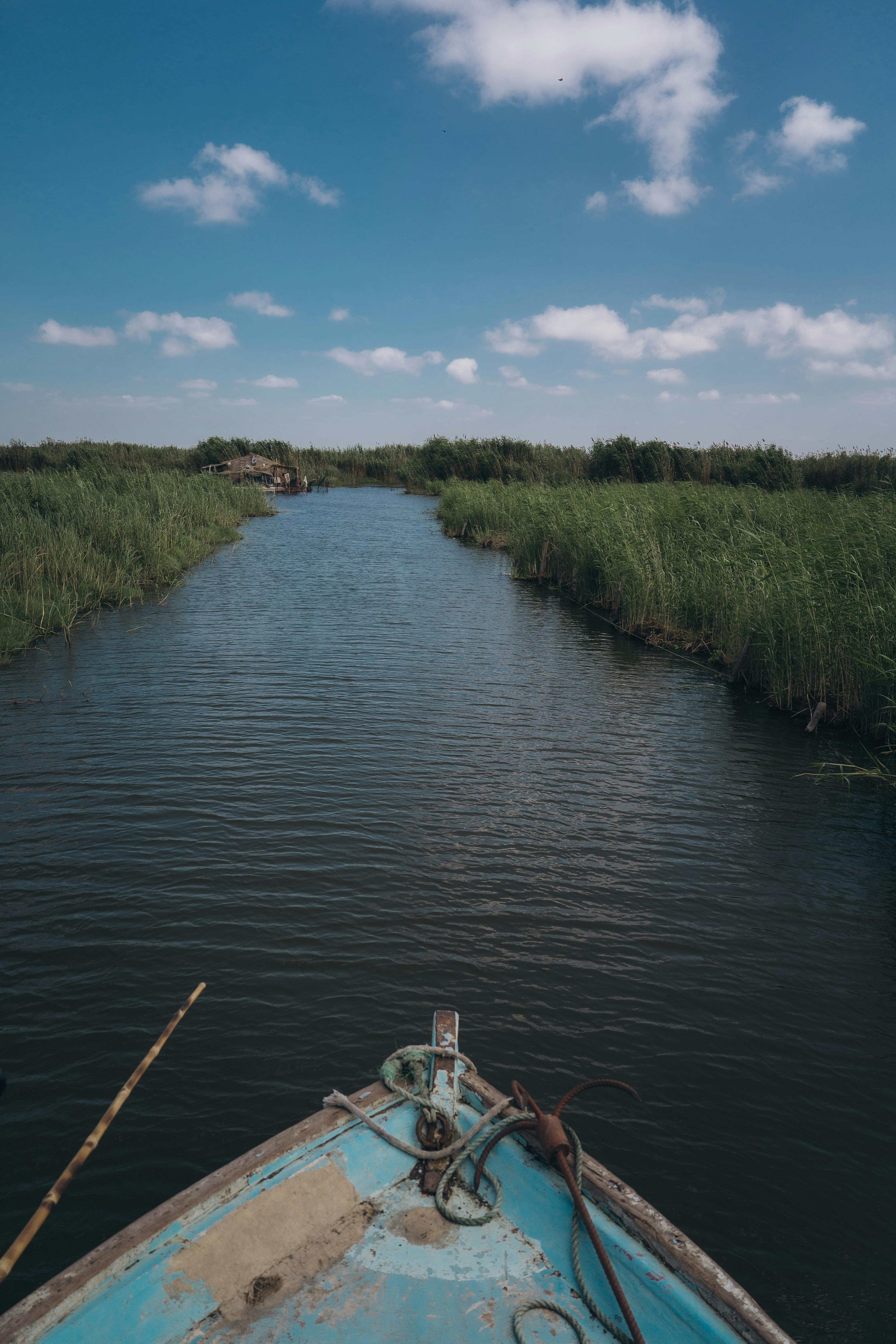 a boat is traveling down a river with grass and water