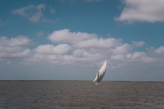 A serene view of a sailboat navigating the calm waters with clouds overhead, captured in Kafr El-Shaikh, Egypt.