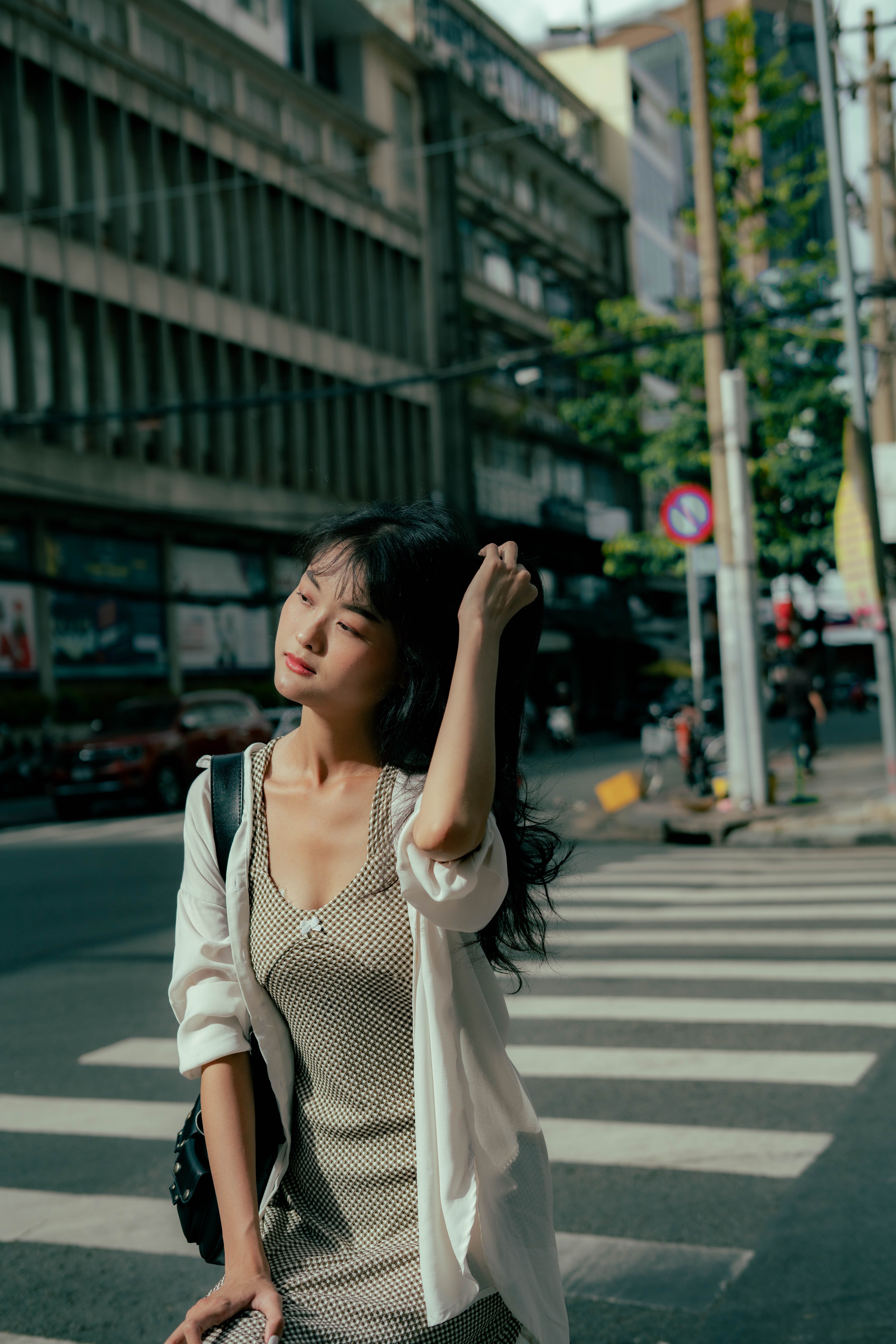 A woman is walking across the street in a city · Free Stock Photo