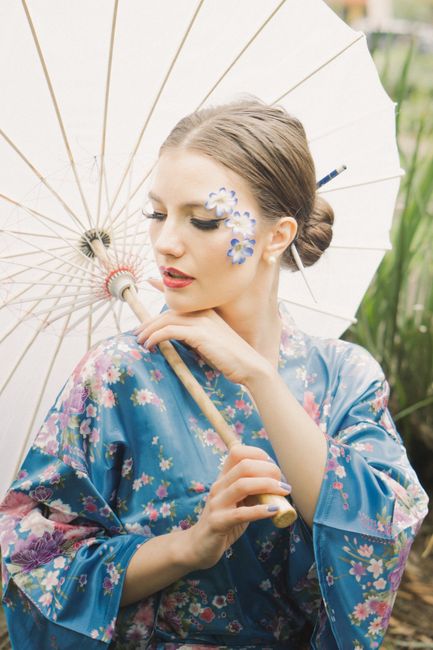 Woman in floral kimono with parasol, enjoying a sunny day in a serene garden.