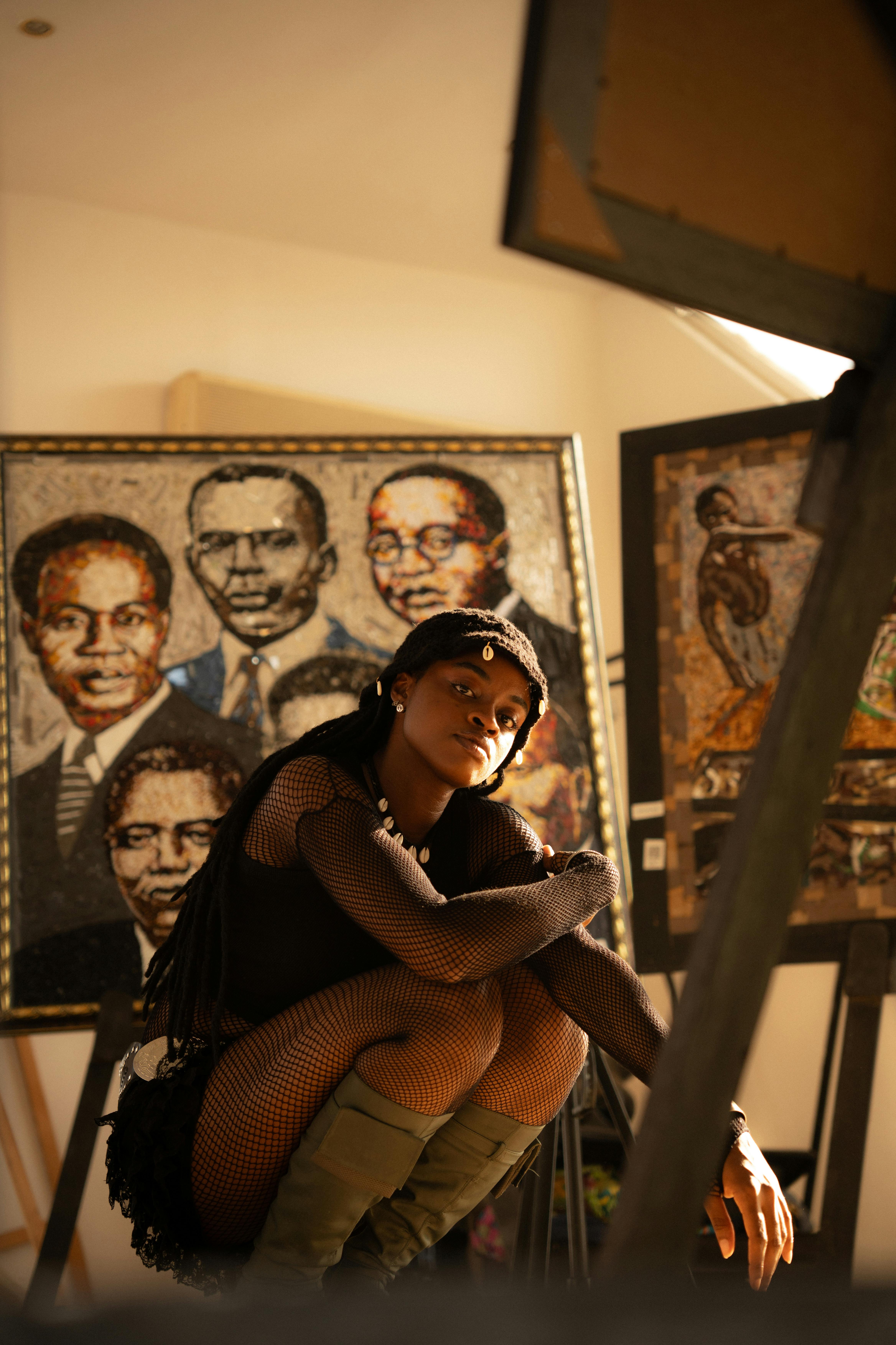 A woman poses stylishly in an art gallery with notable portraits.