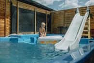 Young child playing with inflatable in a pool with slide during summer.