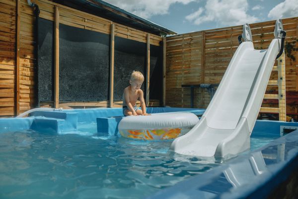 Kind speelt op opblaasbare waterslide met zwembad
