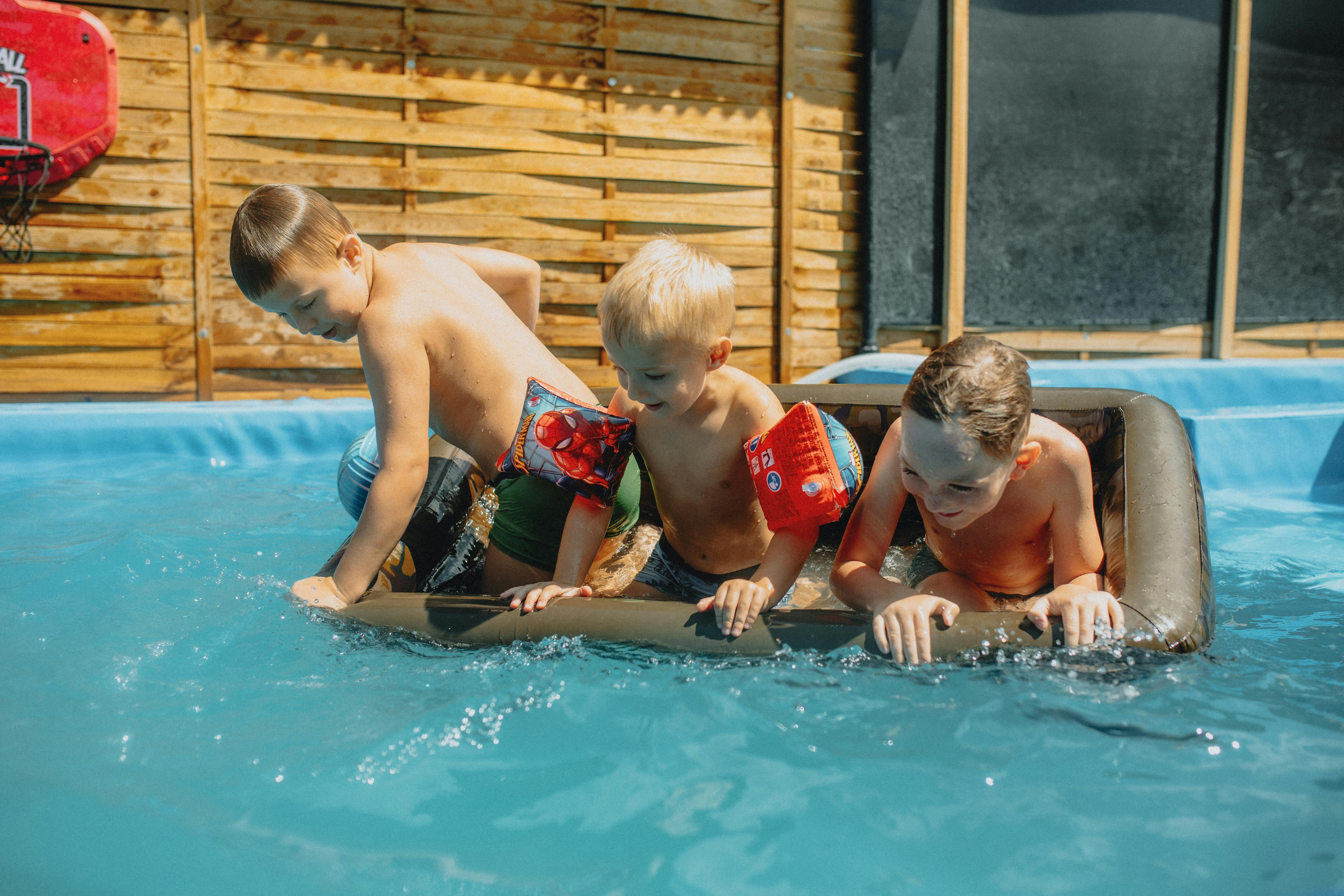 three boys playing in a pool with an inflatable raft