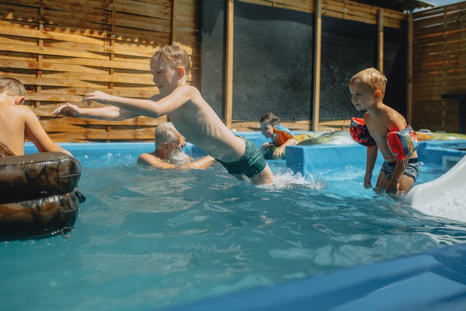 Des enfants profitent d'une journée de jeux dans une piscine de jardin, s'éclaboussant et nageant sous le soleil.