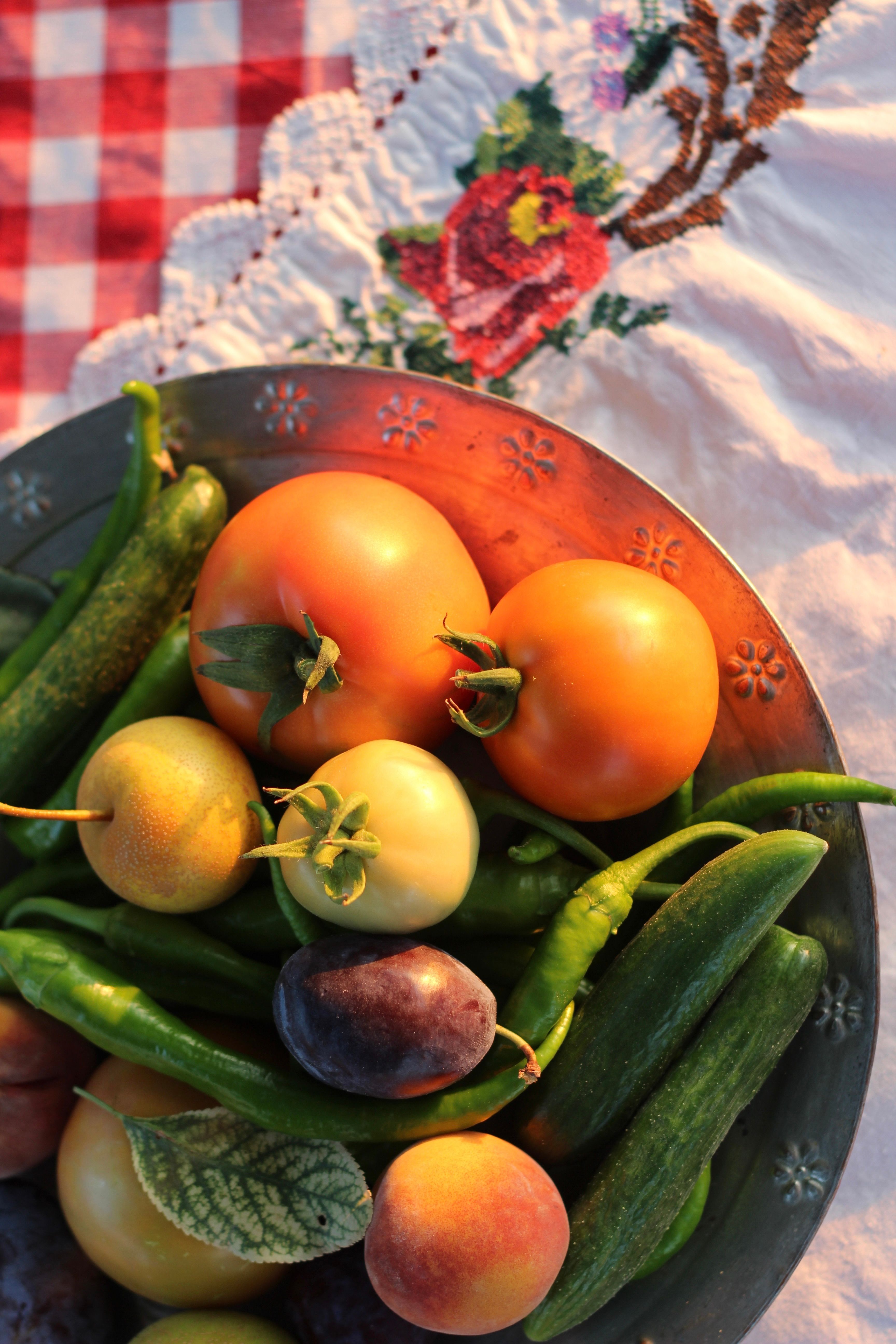 Vibrant mix of tomatoes, peppers, and fruits on a rustic dish with a floral tablecloth.