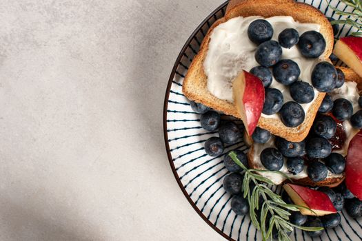 Top-down view of toast with blueberries, cream, and apples on a stylish plate. Perfect breakfast idea.