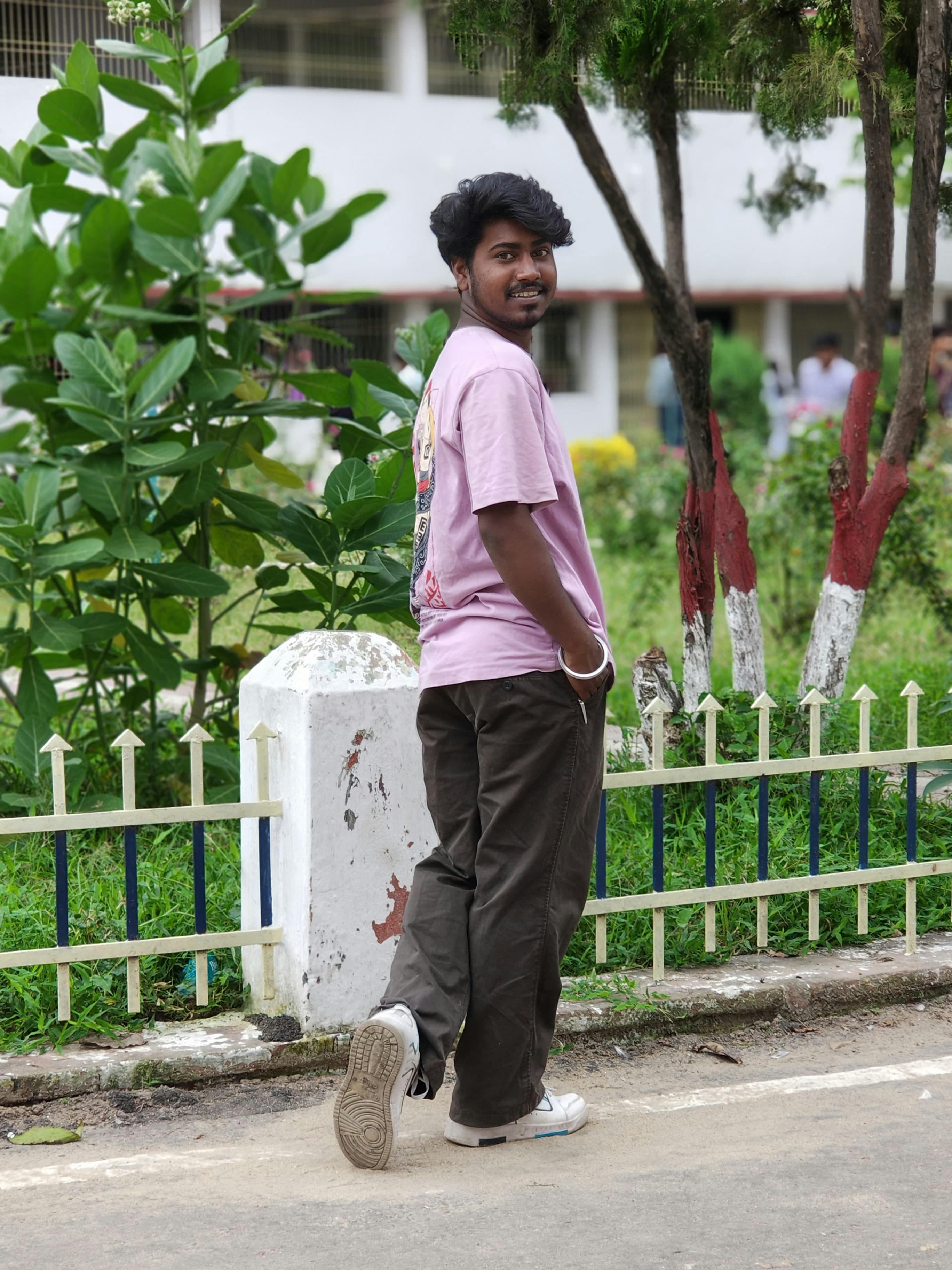 a man in pink shirt standing on a street