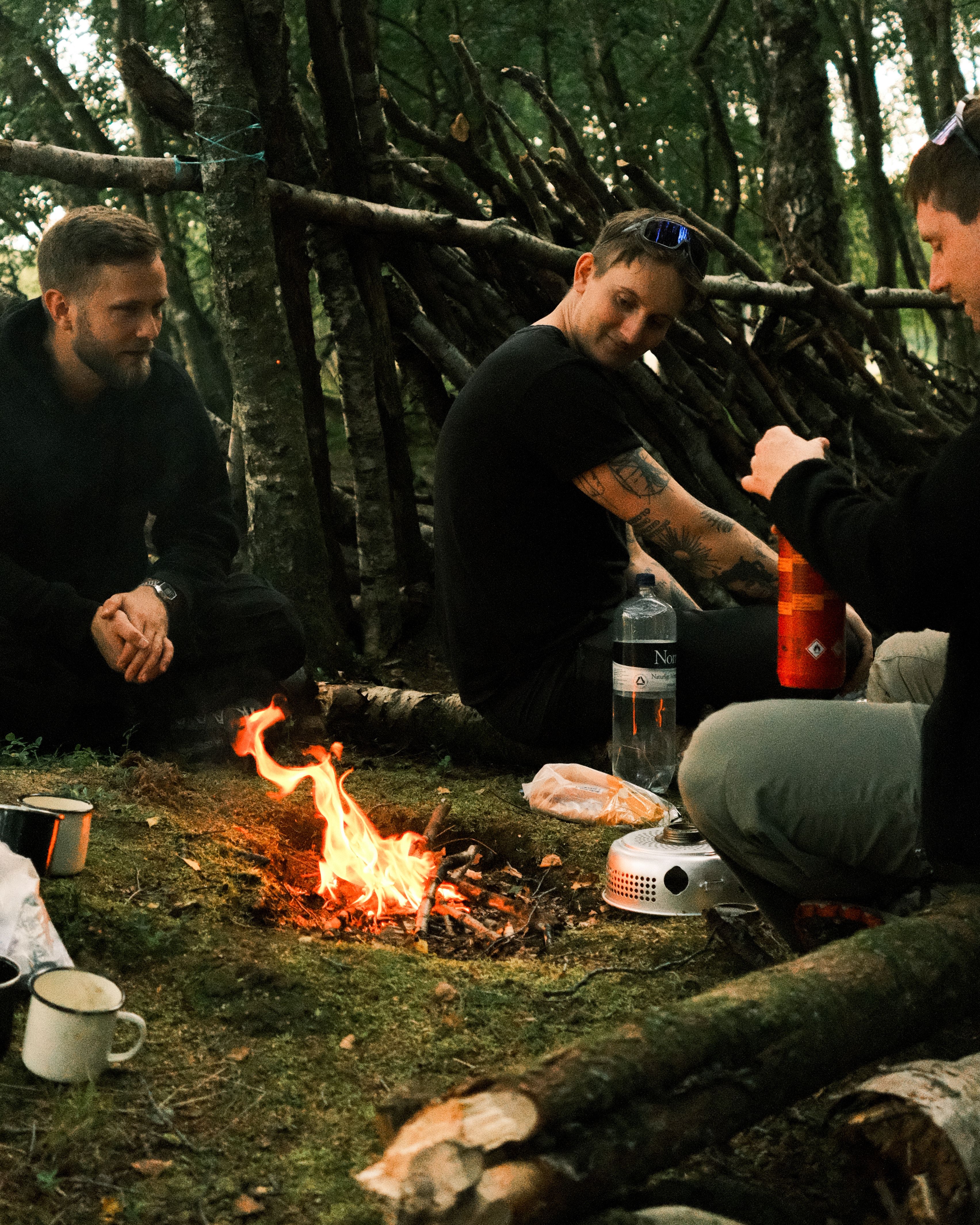 Three men sitting around a campfire in the woods · Free Stock Photo