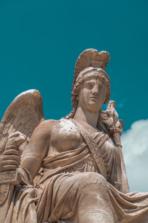 Free Intricate marble statue of a winged archangel against a clear sky. Renaissance art detail. Stock Photo