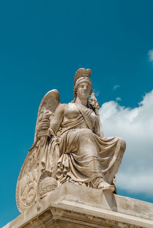 Free Classic marble angel statue with shield, symbolizing protection, set against a vibrant blue sky. Stock Photo