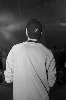 Monochrome image of a man from behind at a dark concert event.