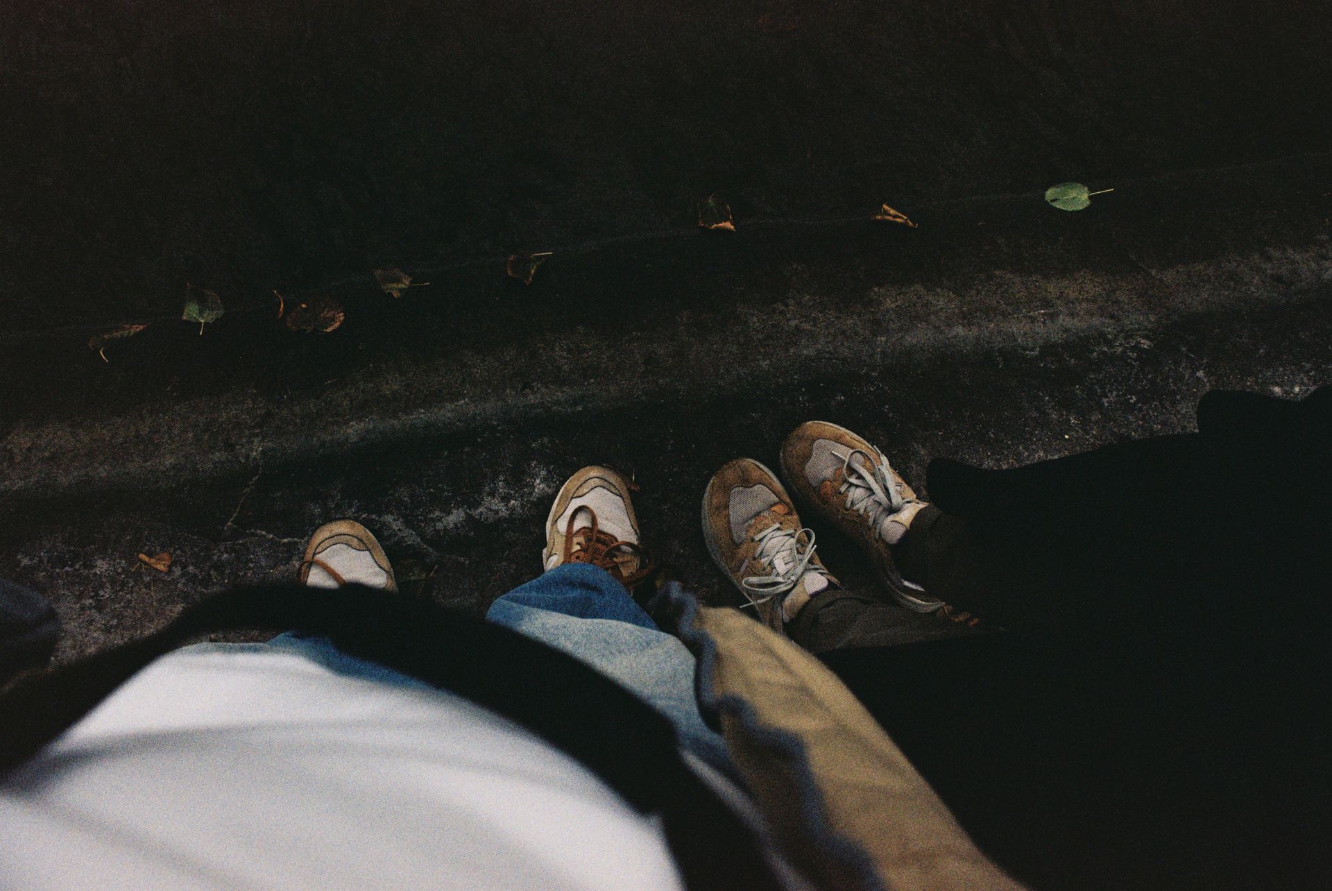 Overhead view of two pairs of sneakers on a gritty city sidewalk.