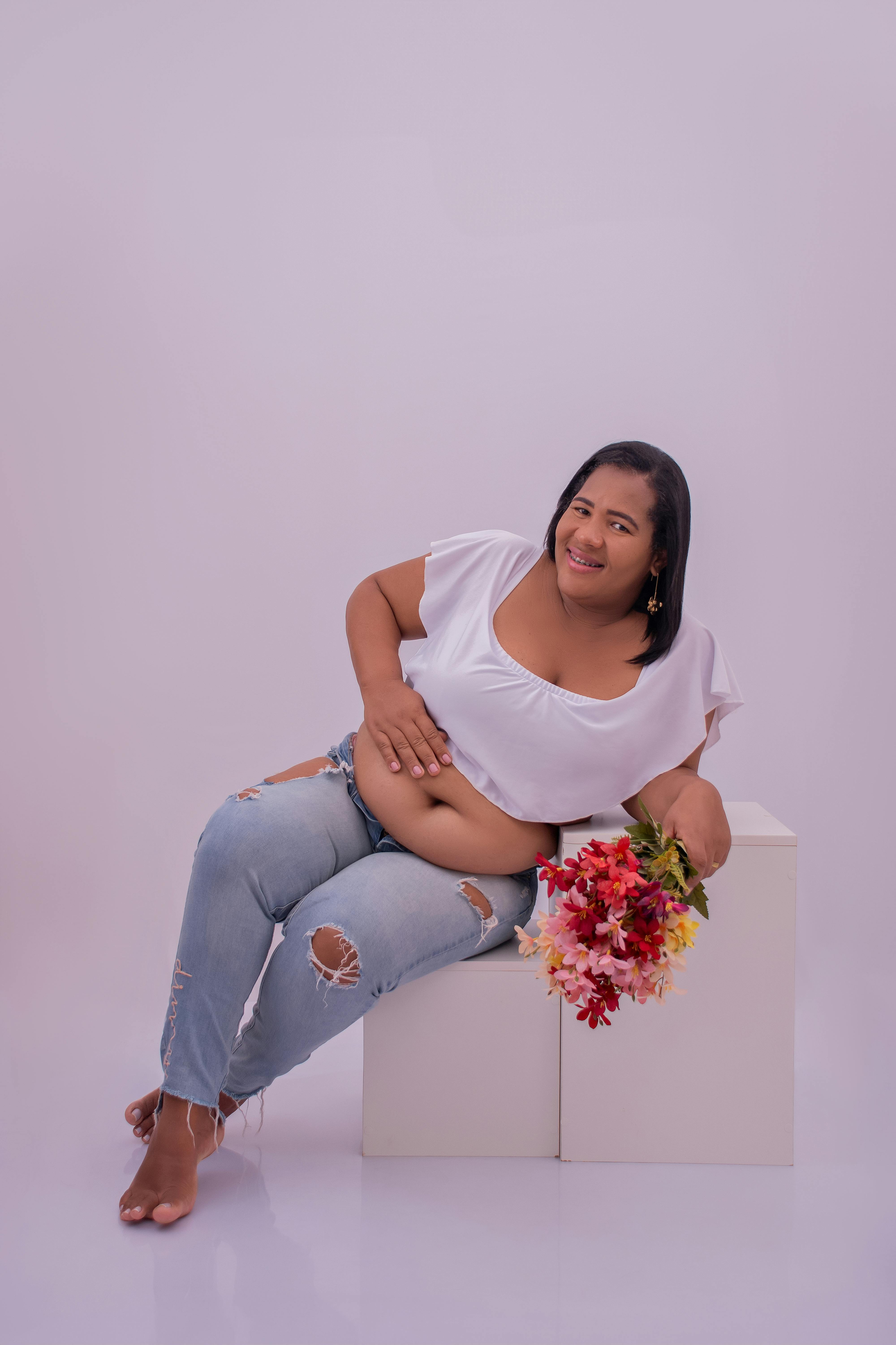 a pregnant woman sitting on a white box with flowers