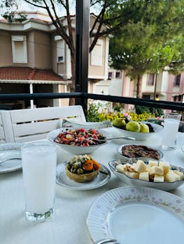 Enjoy a vibrant Mediterranean meal outdoors with fresh fruits, salads, and drinks on a sunny day.